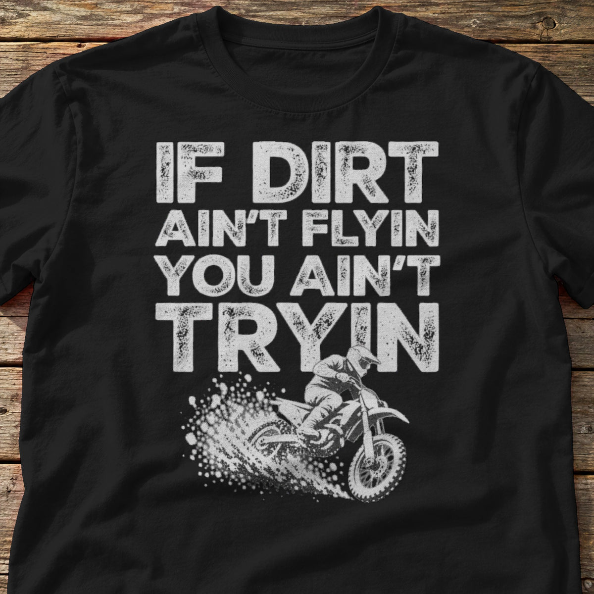 If Dirt Ain't Flyin You Ain't Tryin t-shirt in Black, laid flat on weathered wood