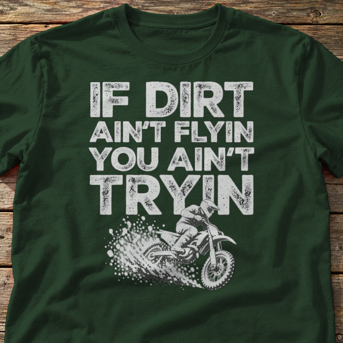 If Dirt Ain't Flyin You Ain't Tryin t-shirt in Forest Green, laid flat on weathered wood