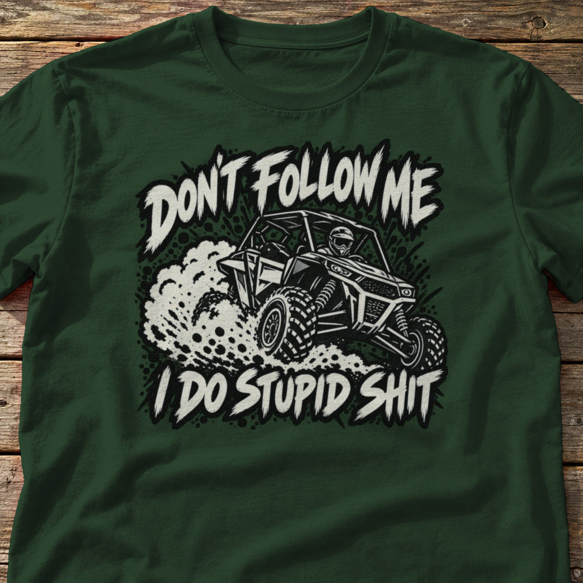 Don't Follow Me I Do Stupid Shit t-shirt in Forest Green, laid flat on weathered wood