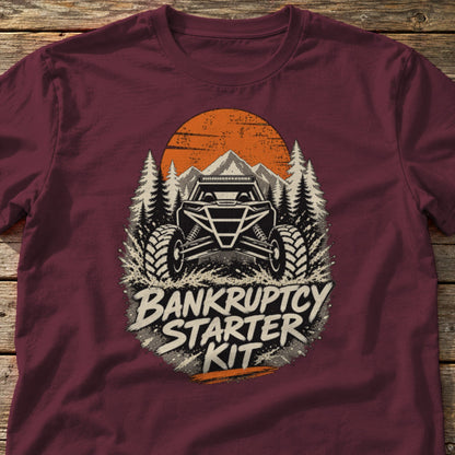 Bankruptcy Starter Kit t-shirt in Maroon, laid flat on weathered wood