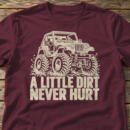 A Little Dirt Never Hurt t-shirt in Maroon, laid flat on weathered wood