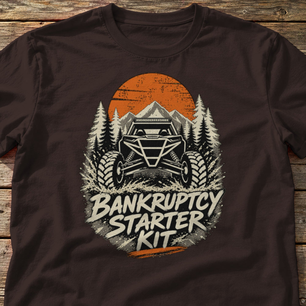 Bankruptcy Starter Kit t-shirt in Dark Chocolate, laid flat on weathered wood