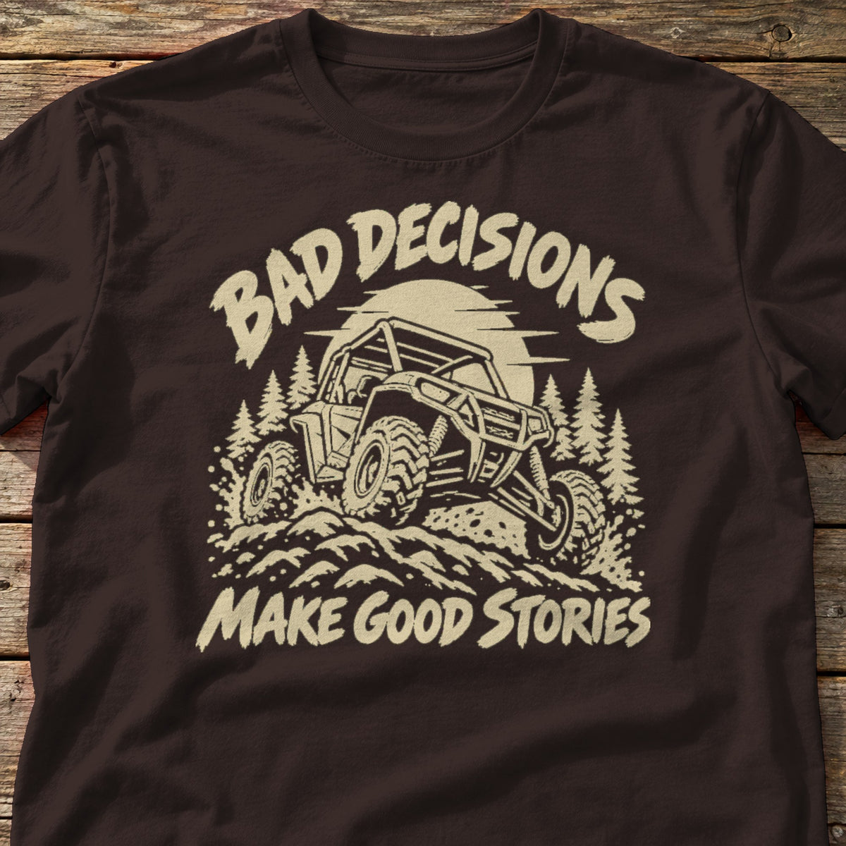 Bad Decisions Make Good Stories t-shirt in Dark Chocolate, laid flat on weathered wood