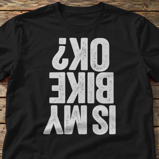 Is My Bike OK? t-shirt in Black, laid flat on weathered wood
