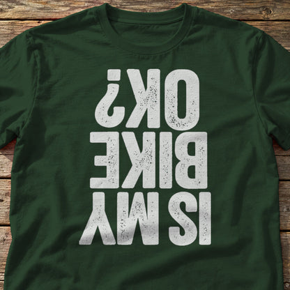 Is My Bike OK? t-shirt in Forest Green, laid flat on weathered wood