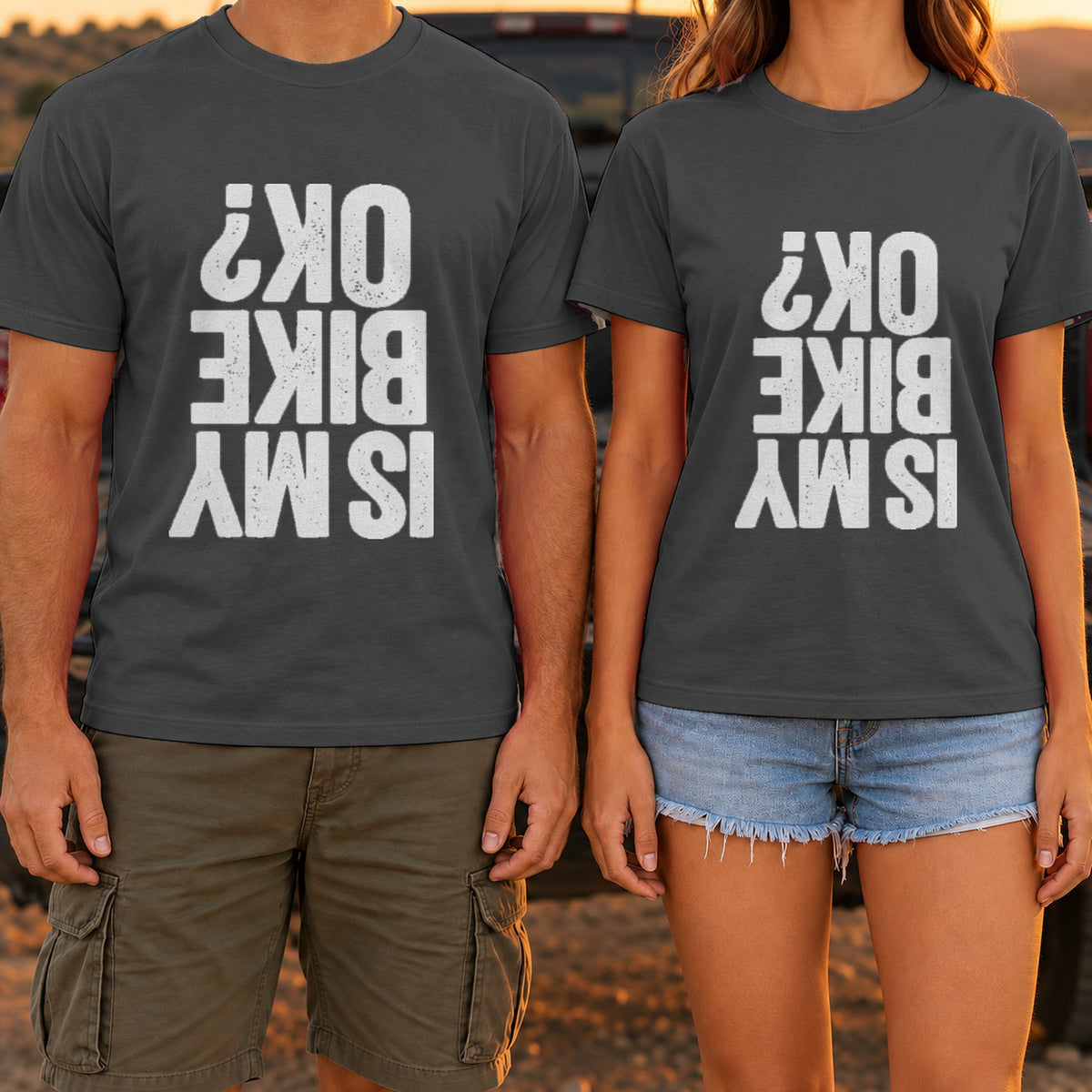 Is My Bike OK? t-shirt in Dark Heather, worn by a couple at a truck tailgate